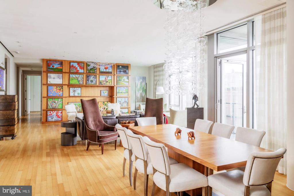 Condominium living and dining area with a long wood table, crystal chandelier, and colorful artwork shelves.