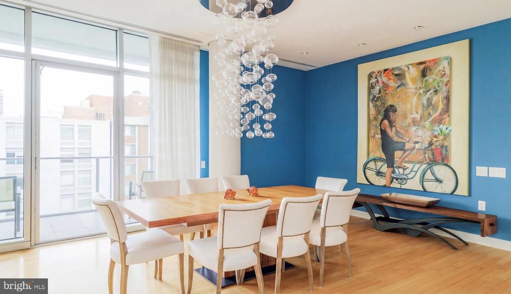Dining room with a wooden table, white chairs, blue walls, and sliding glass doors to a balcony.