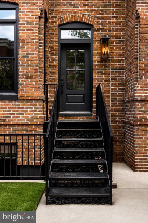 Brick townhouse entrance with an arched doorway and ornate black iron steps.