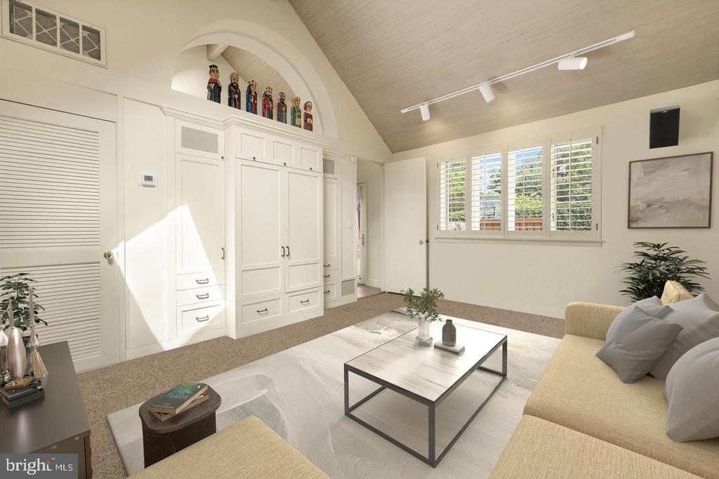 Living room with vaulted ceiling, built-in cabinetry, shuttered windows, and a light sofa.