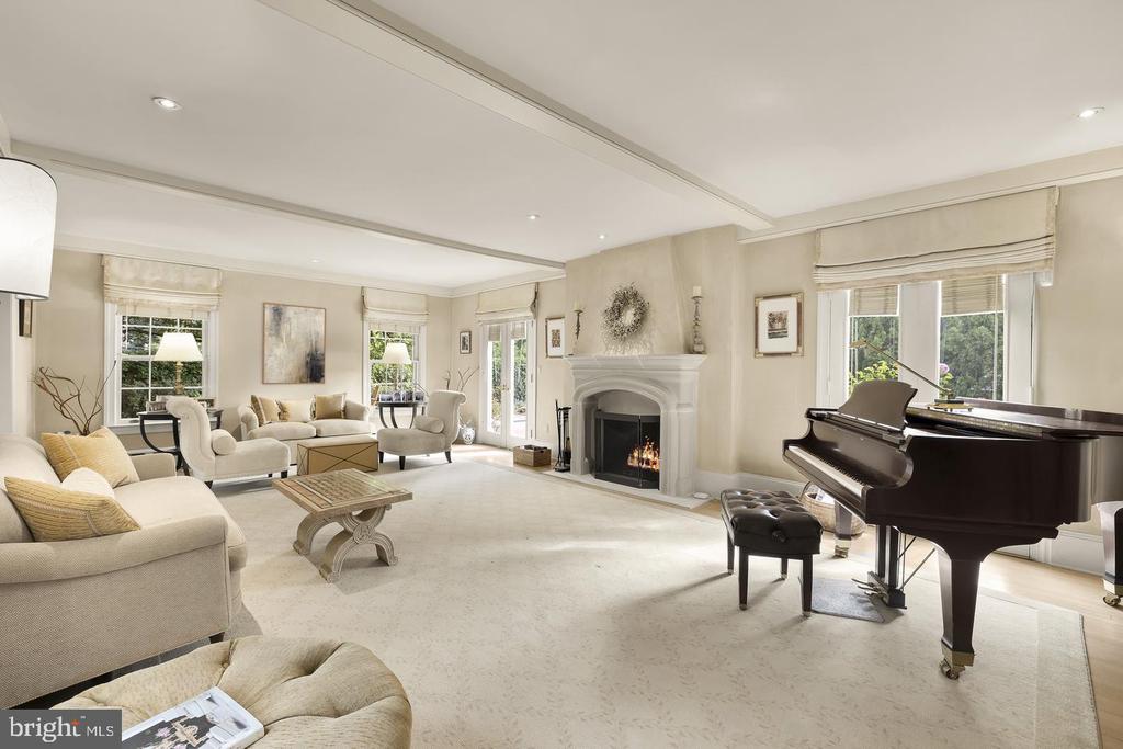 Living room with a white fireplace, cream seating, and a black grand piano.
