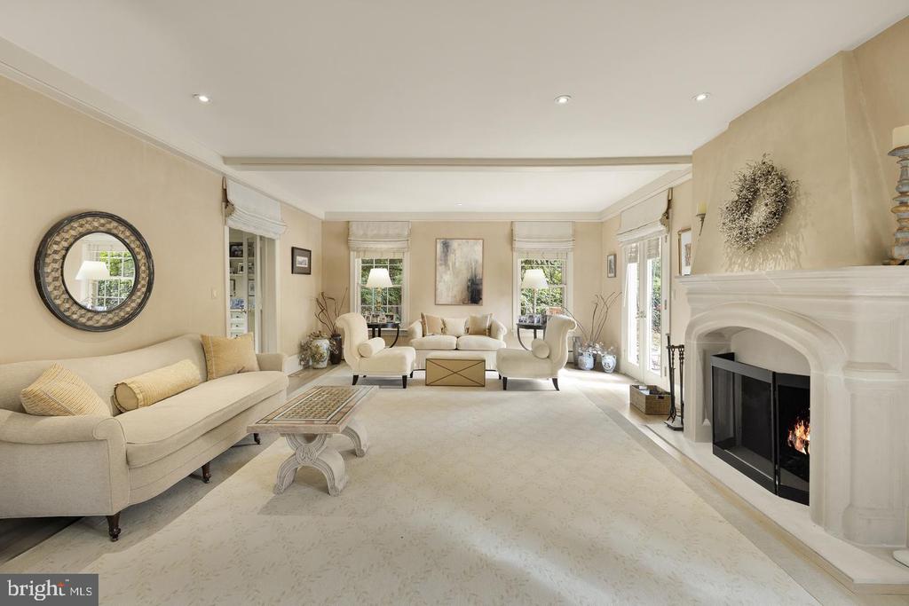 Furnished living room with cream seating, a white fireplace, and large windows.