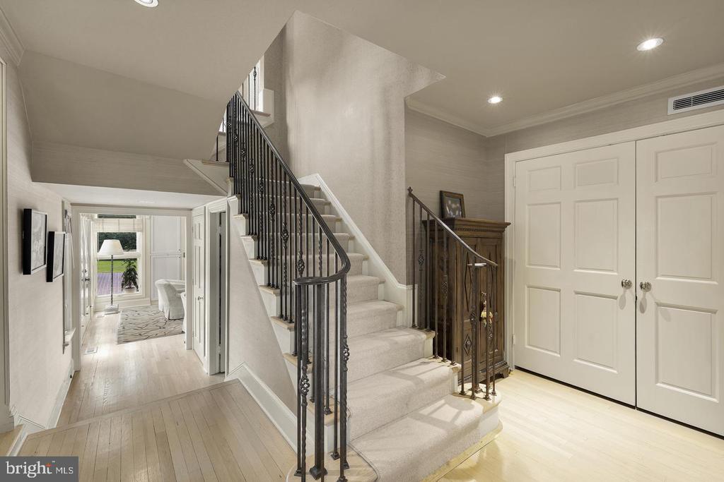 Entry foyer with a carpeted staircase, ornate iron railing, and white double doors.