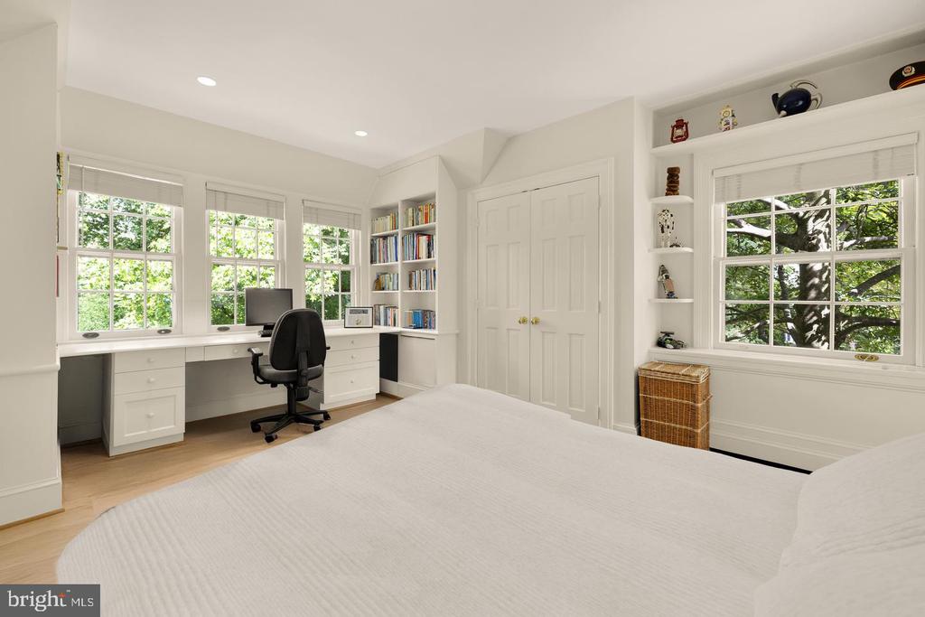 Bedroom with a built-in window desk, bookshelves, and leafy views.