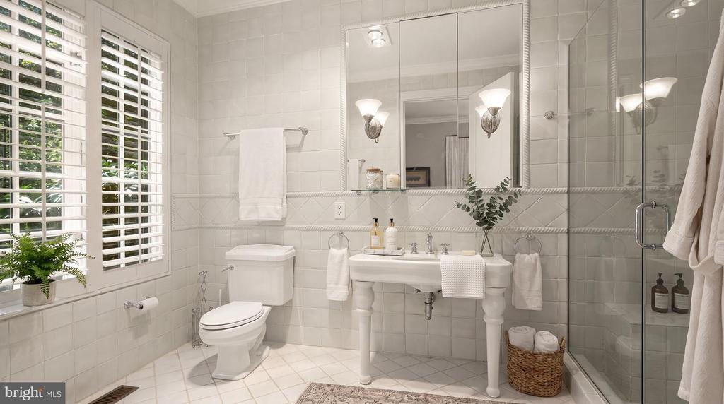 Bright tiled bathroom with a pedestal sink, glass shower, and white plantation shutters.