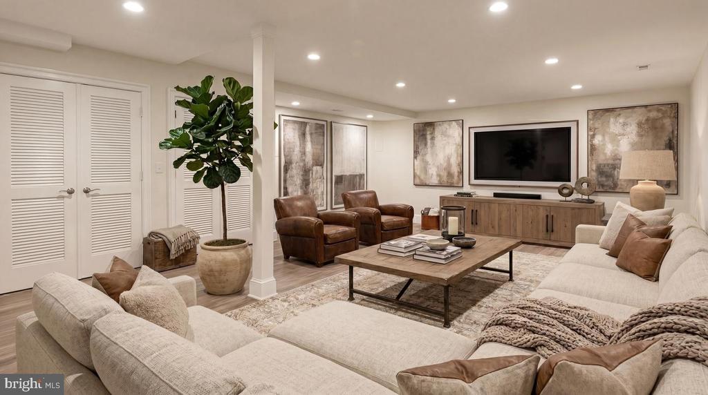 Staged living room with a cream sectional, leather armchairs, and a wall-mounted television.