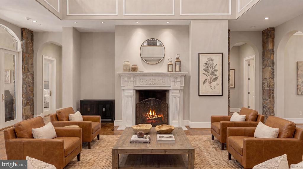 Living room with a lit ornate fireplace, brown leather sofas, and stone-clad columns.