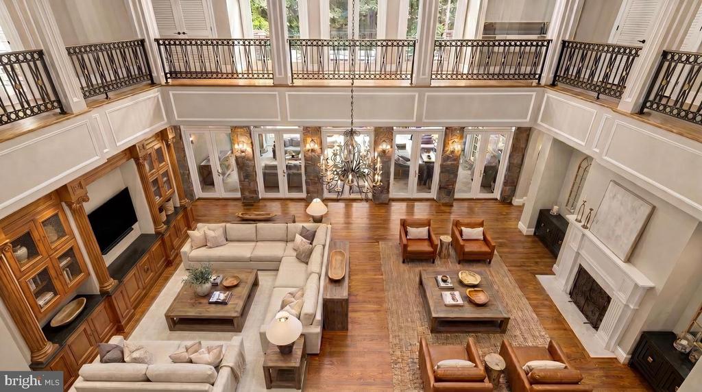Two-story living room with a large sectional, built-in wood cabinetry, and iron balcony railing.
