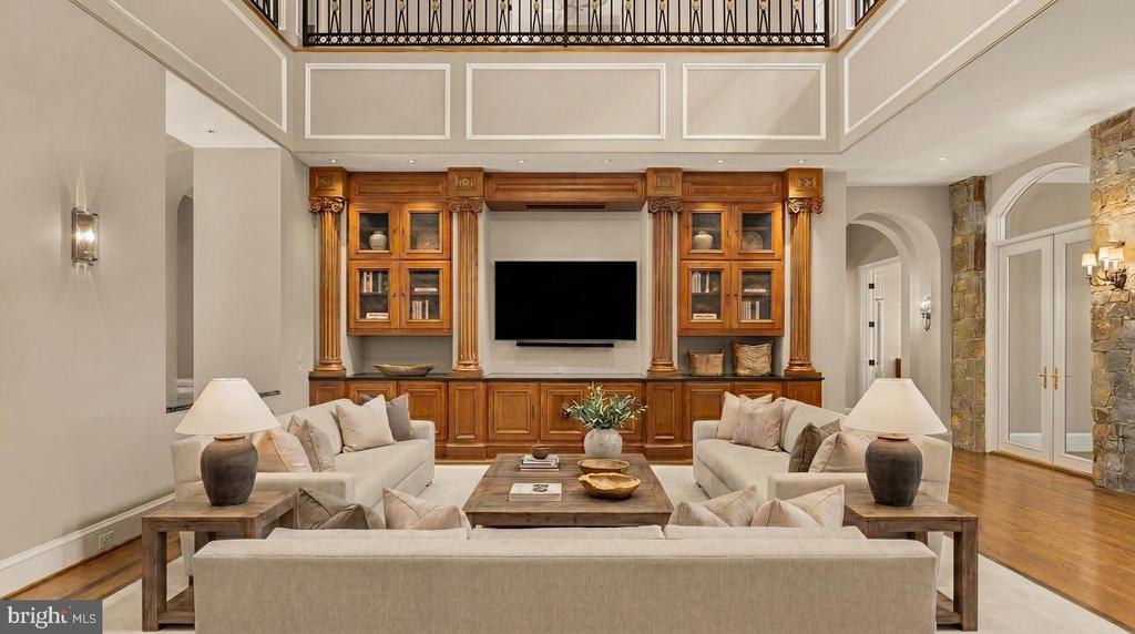 Furnished living room with ornate wood built-ins, central television, and a high ceiling.
