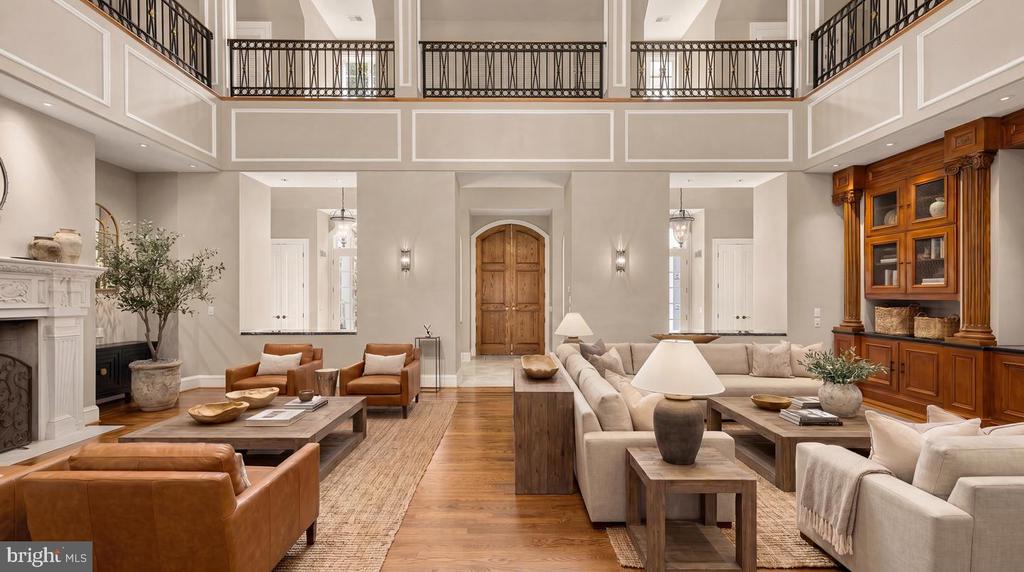 Two-story living room with a fireplace, upper-level balcony, and built-in wood cabinetry.