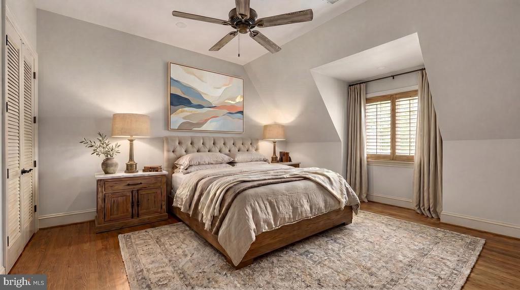 Attic bedroom with a wooden bed, tufted headboard, abstract artwork, and shuttered windows.