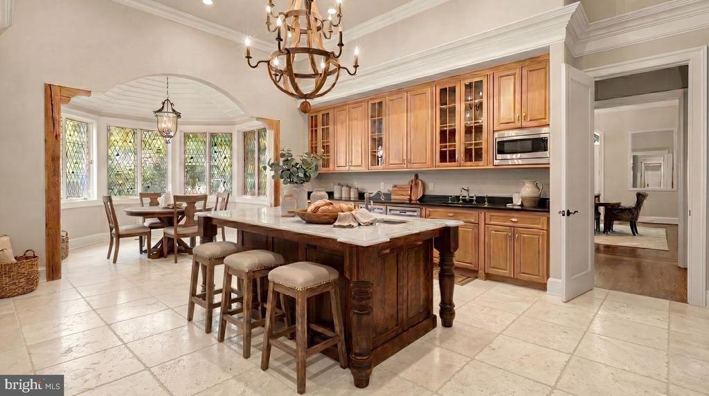 Kitchen with a large marble-topped island, warm wood cabinetry, and adjoining dining area.