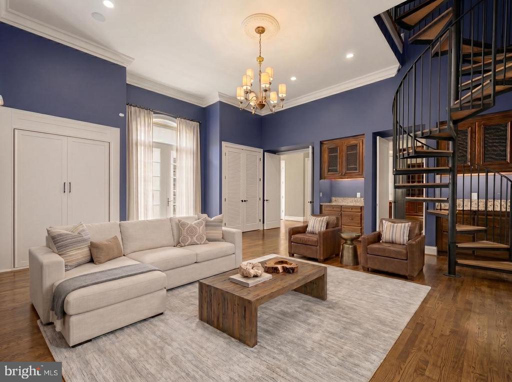 Living room with blue walls, a cream sectional, leather chairs, and a spiral staircase.
