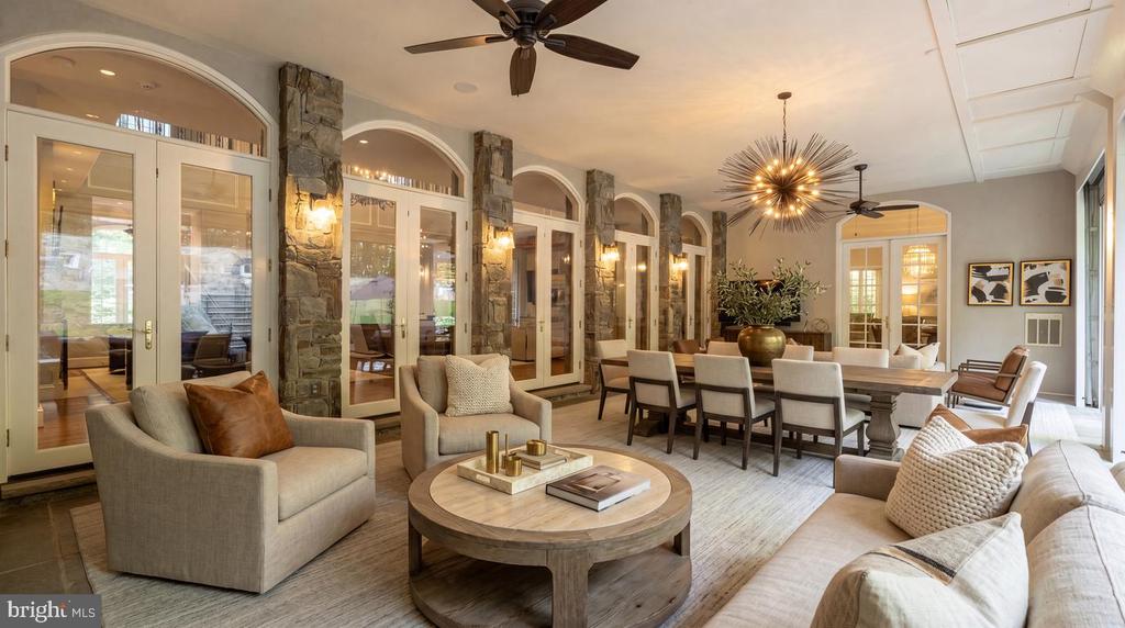 Living and dining room with arched glass doors, stone columns, and a starburst chandelier.