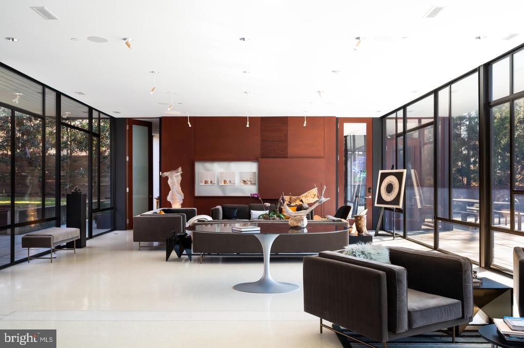 Contemporary living room with floor-to-ceiling glass walls and a dark wood-paneled feature wall.