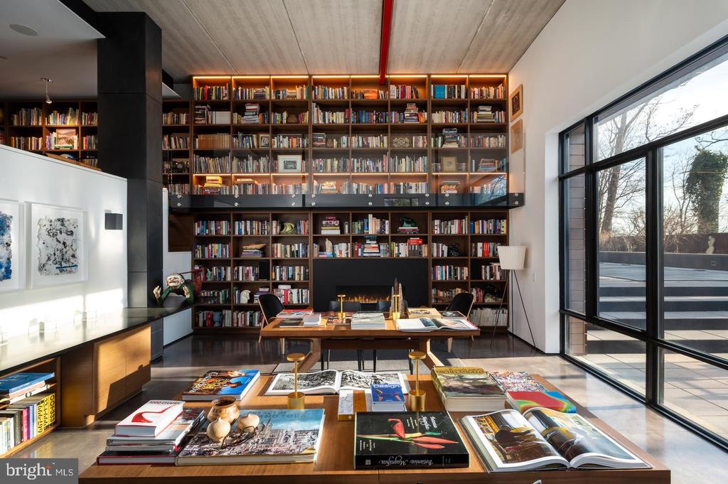 Library with floor-to-ceiling bookshelves, a fireplace, and large windows.