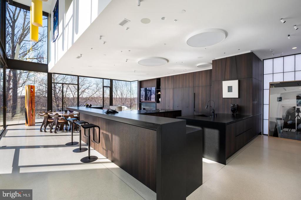 Modern kitchen with a large dark island, bar stools, and floor-to-ceiling windows.