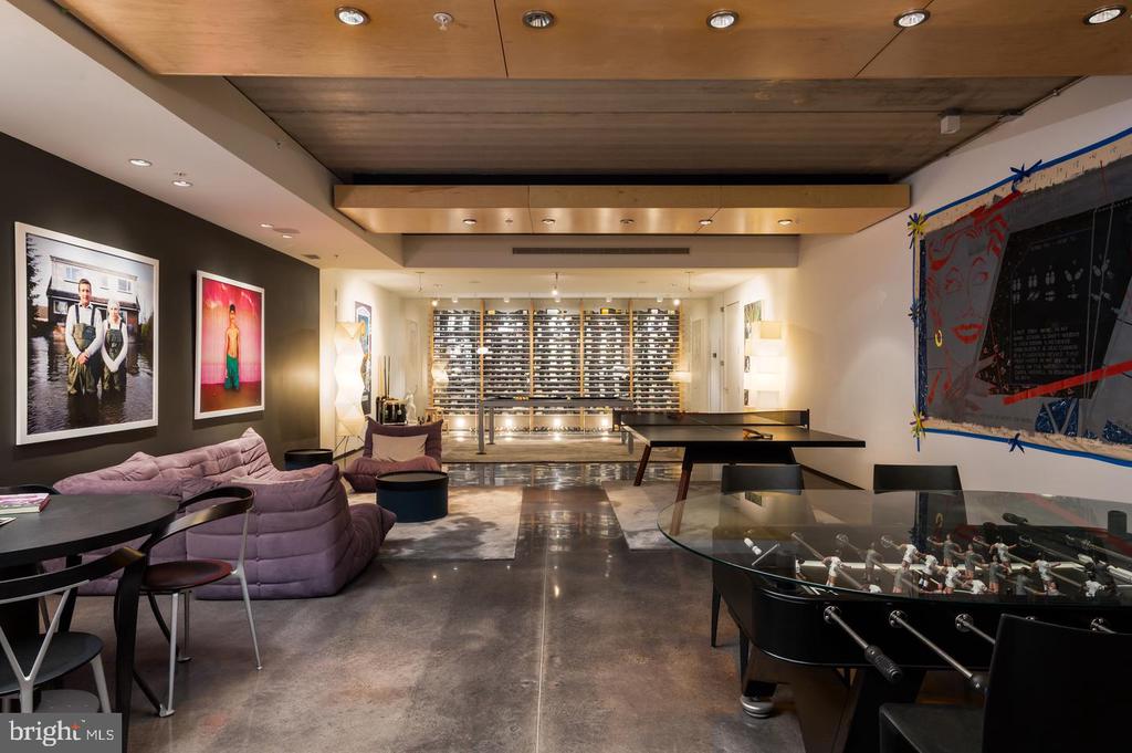 Game room with a wine display wall, ping-pong table, foosball table, and purple lounge seating.
