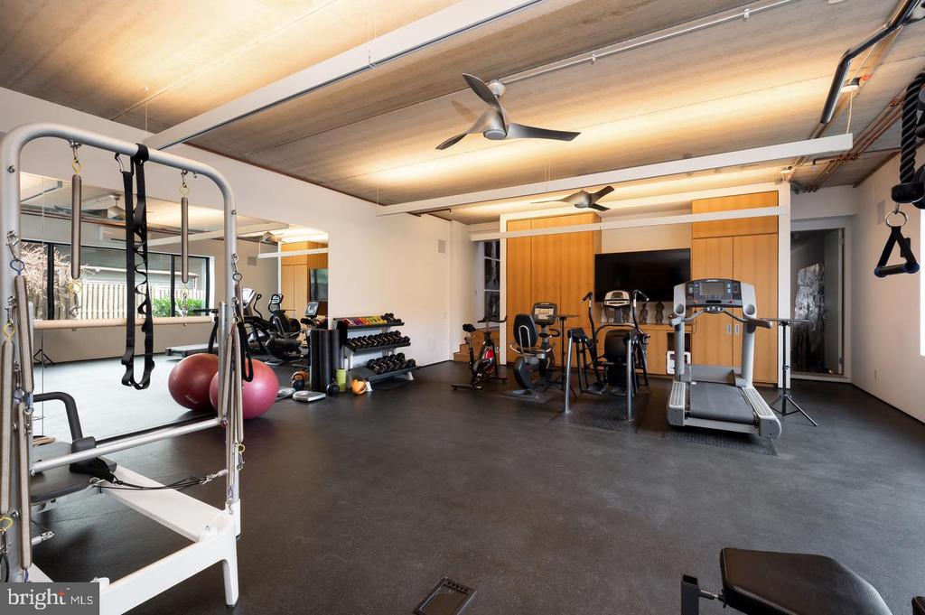 Home gym with a treadmill, weight racks, stationary bikes, and a Pilates reformer.