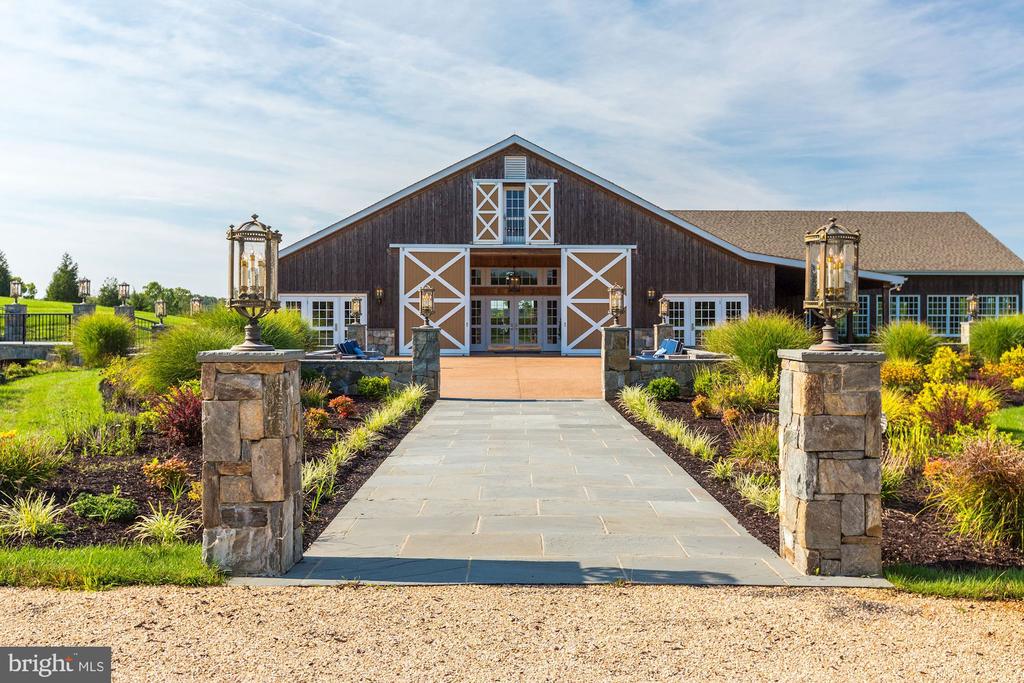 Barn-style building with white crossbuck trim at the end of a stone walkway.