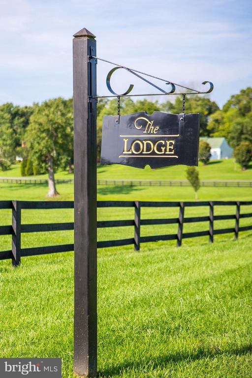 The Lodge sign beside a black fence on a green lawn.