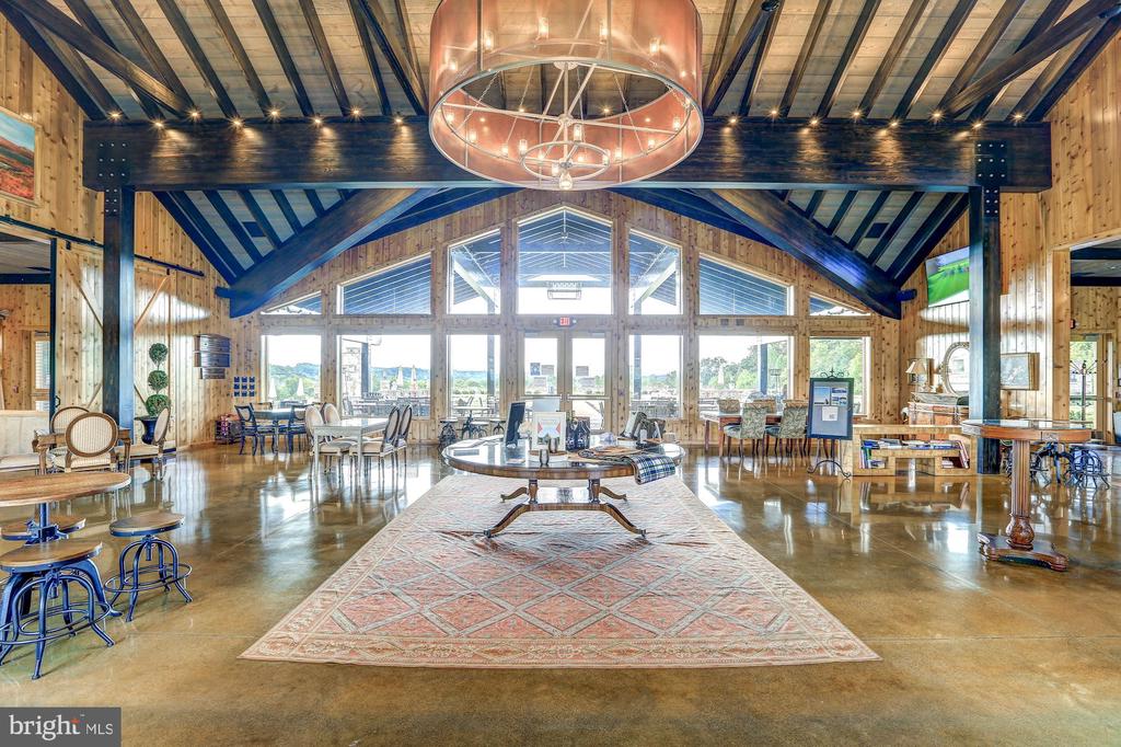 Furnished great room with exposed timber beams, a large chandelier, and expansive windows.
