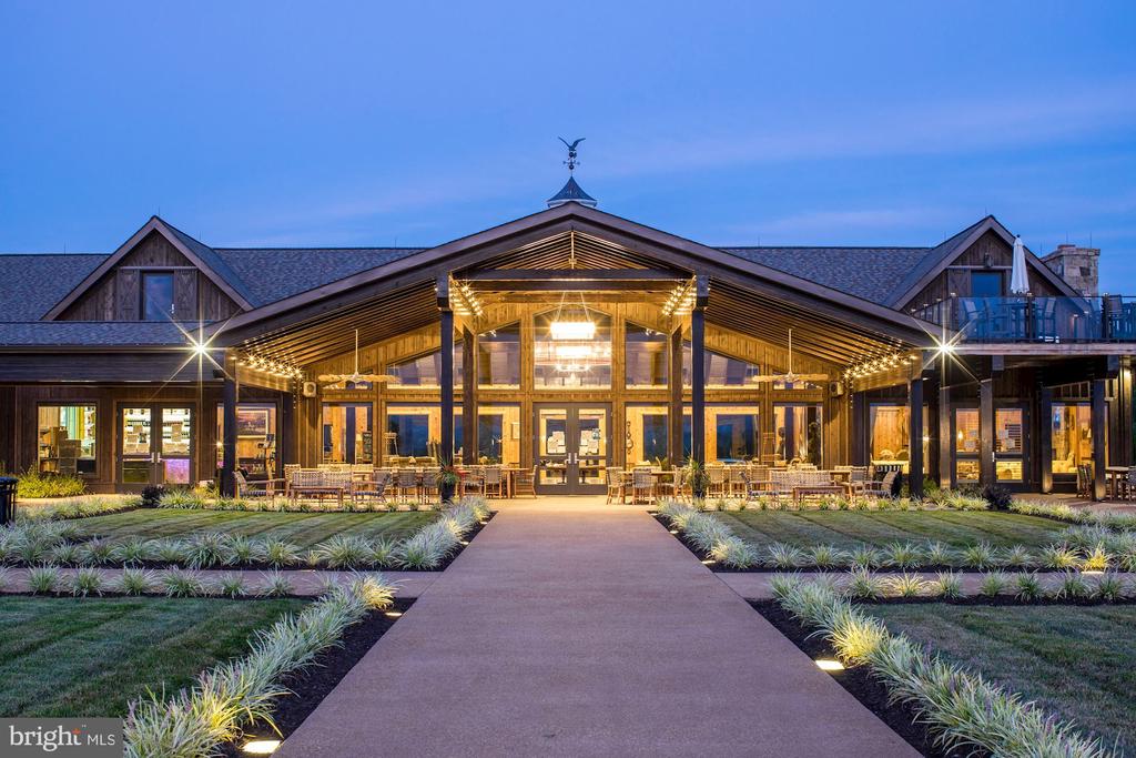 Front exterior of a timber lodge-style building, warmly lit at dusk with a landscaped walkway.