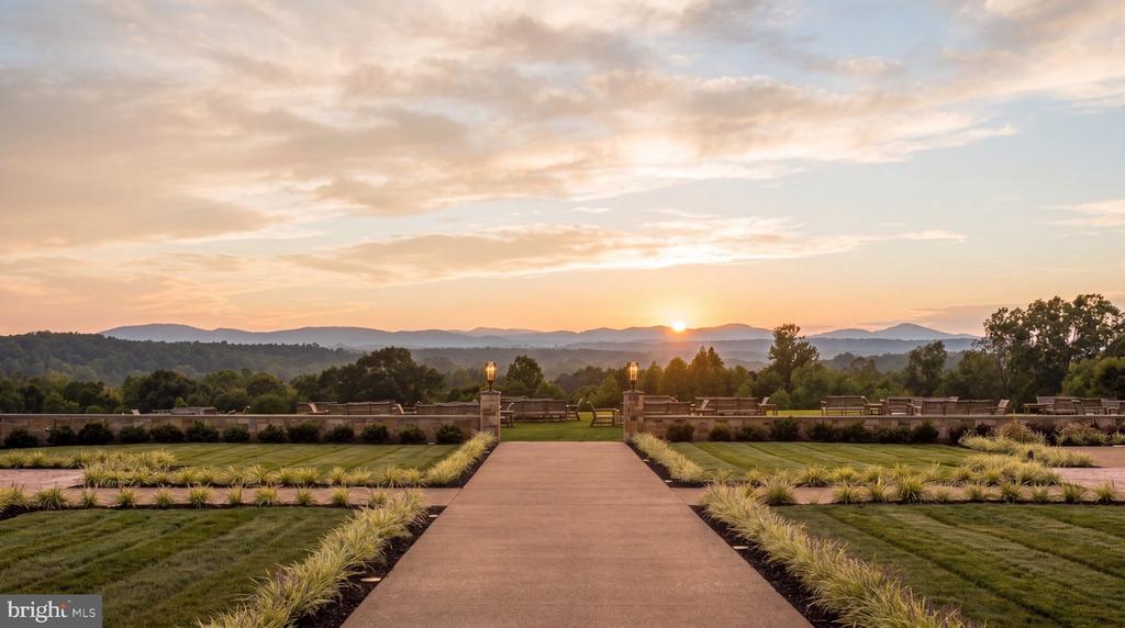 Landscaped walkway leads toward mountain ridges at sunset.