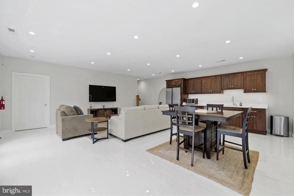 Open-plan living and dining area with dark wood kitchen cabinets and a wall-mounted TV.