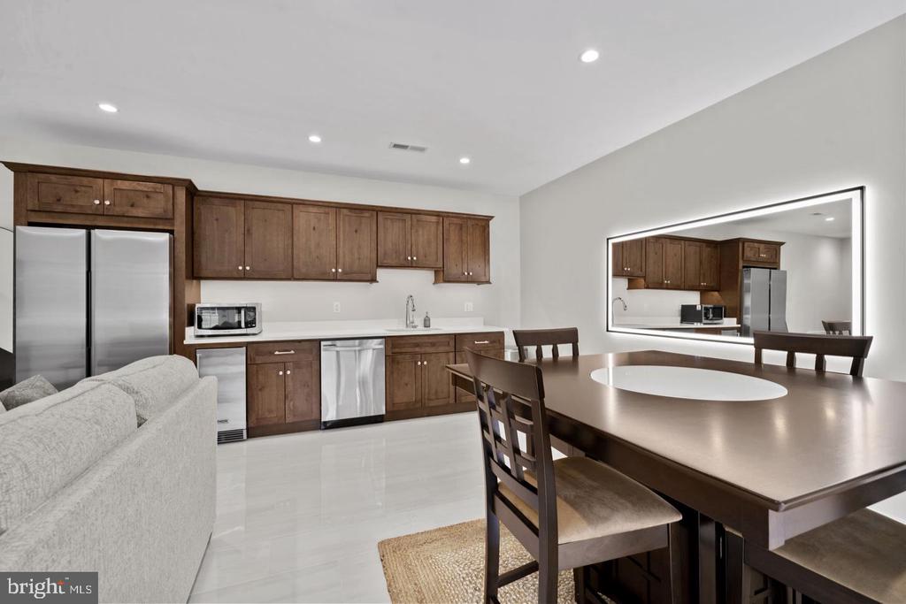 Open kitchen and dining area with dark wood cabinets, stainless steel appliances, and a large dining table.