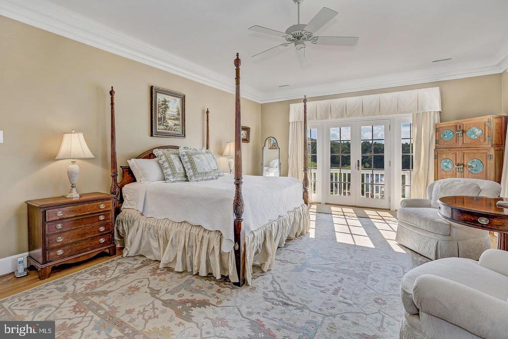 Furnished bedroom with a four-poster bed and French doors overlooking water.