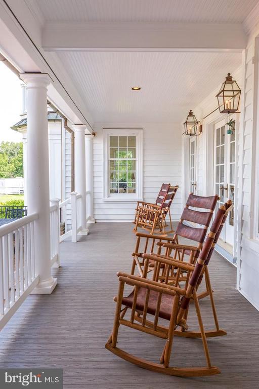Covered porch with wooden rocking chairs, white columns, and hanging lanterns.