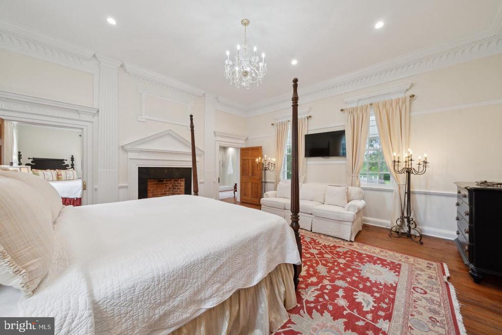 Bedroom with a four-poster bed, brick fireplace, chandelier, and sitting area.