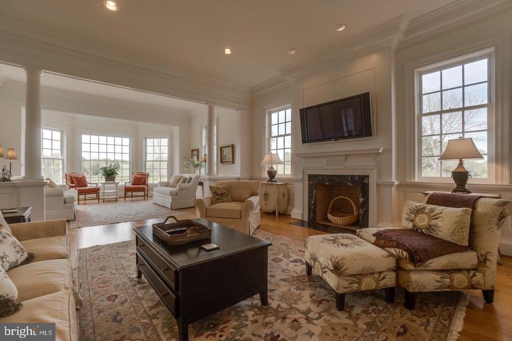 Furnished living room with a fireplace, wall-mounted television, and sunny windowed seating area.