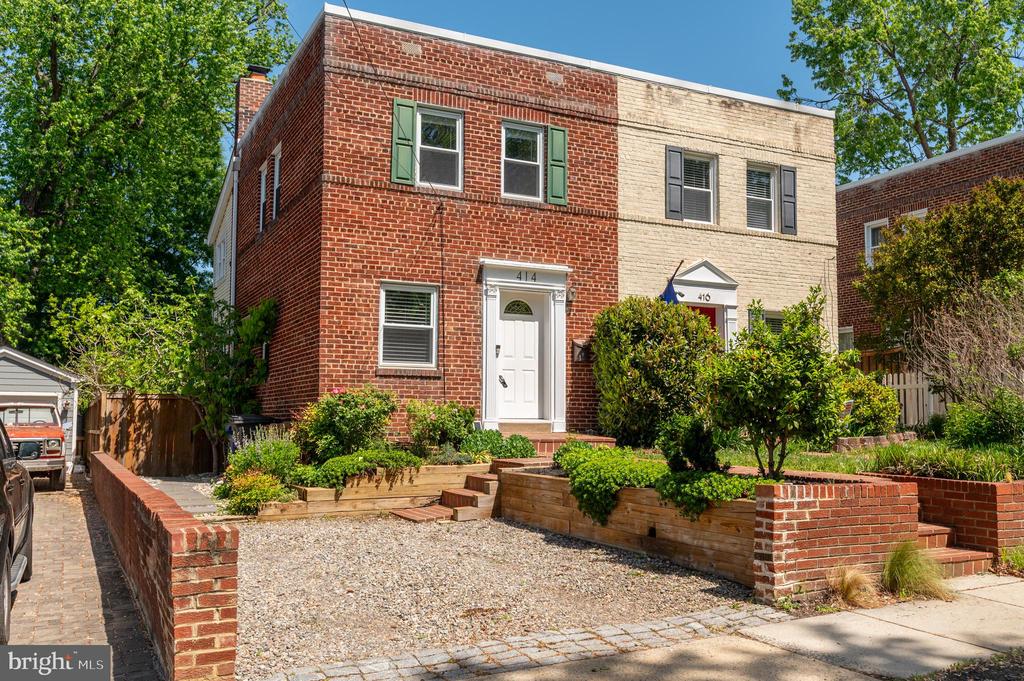 Attached brick homes with white doors and landscaped gravel yards with raised planters.