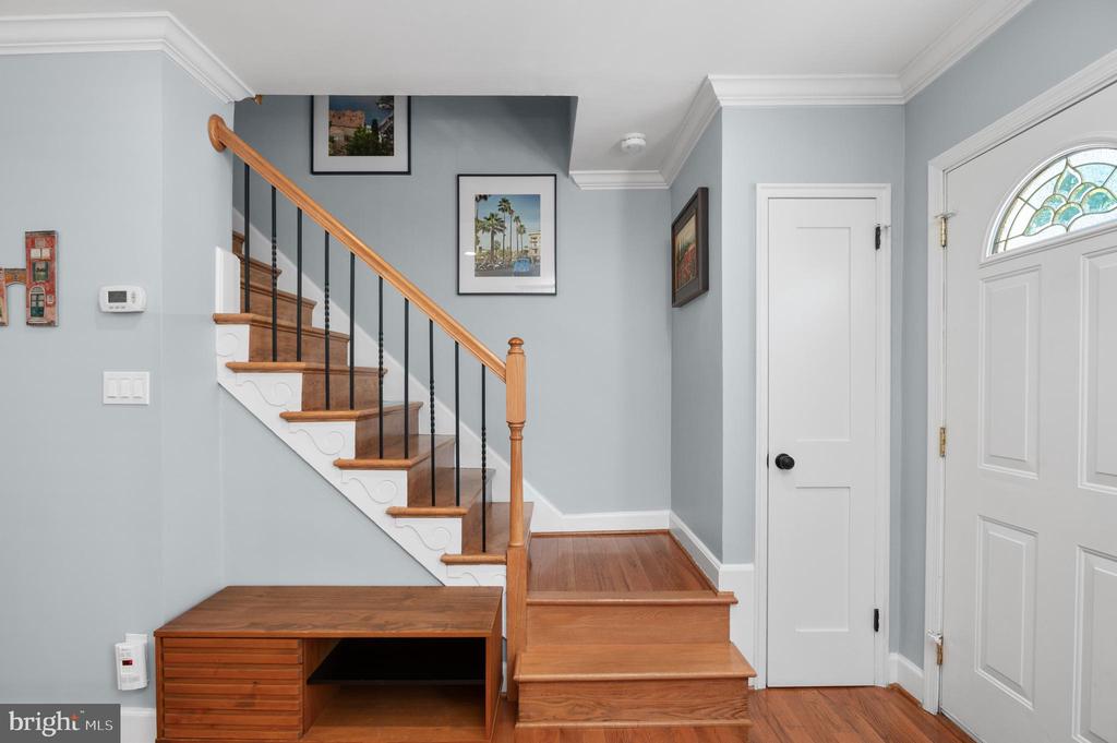 Entry foyer with a wood staircase, built-in bench, and decorative-glass front door.