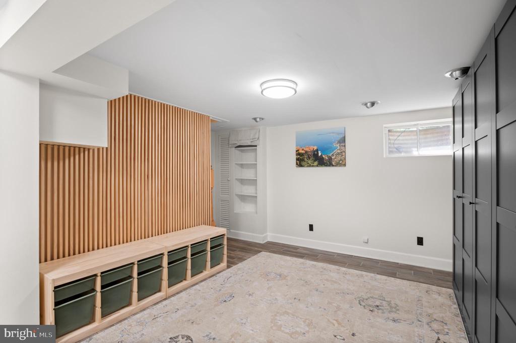 Interior room with a built-in wood bench, slatted wall, dark cabinets, and patterned rug.