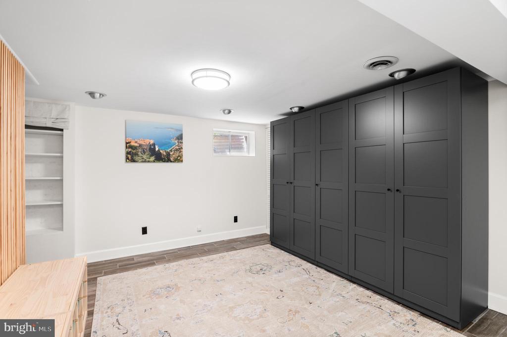 Closet with dark paneled cabinets, open shelving, and a pale area rug.