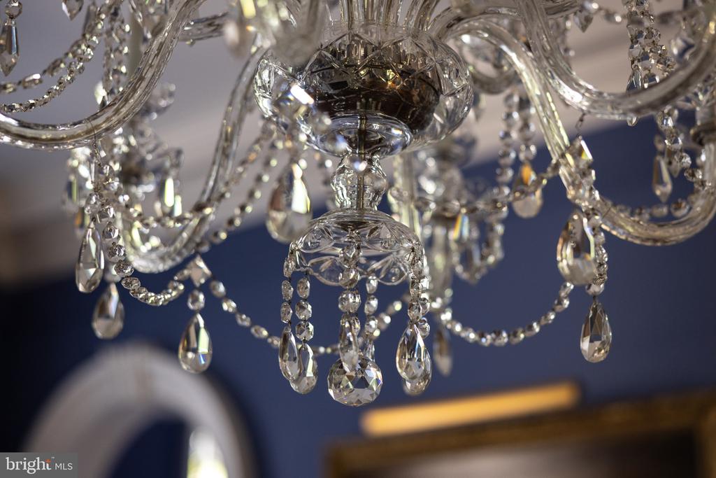 Ornate crystal chandelier with curved glass arms and hanging teardrop pendants.