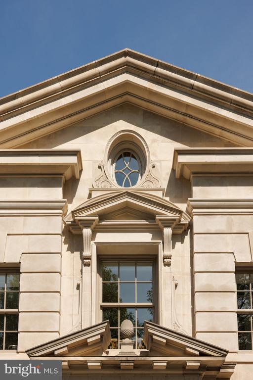 Stone house facade with an oval window above a tall, multi-pane window.