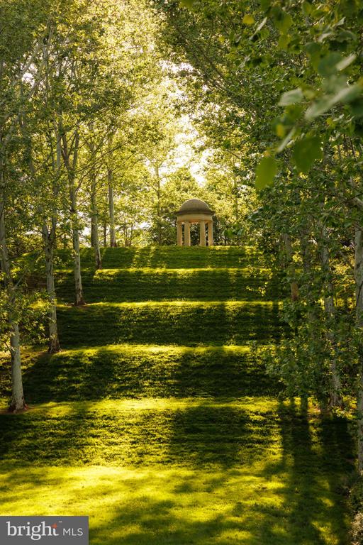 Terraced lawn framed by trees, leading to a small domed garden pavilion.