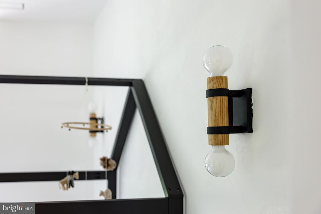 Wood-and-black wall sconce with two exposed bulbs beside a black-framed mirror.