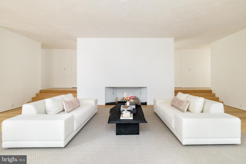 Staged living room with facing white sofas, a black coffee table, and a central fireplace.