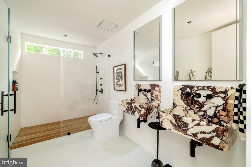 Modern bathroom with a glass walk-in shower and two dramatic marble vessel sinks.