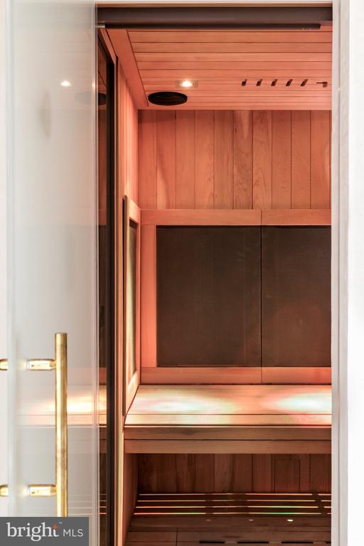 Wood-paneled sauna with built-in benches and a glass door.