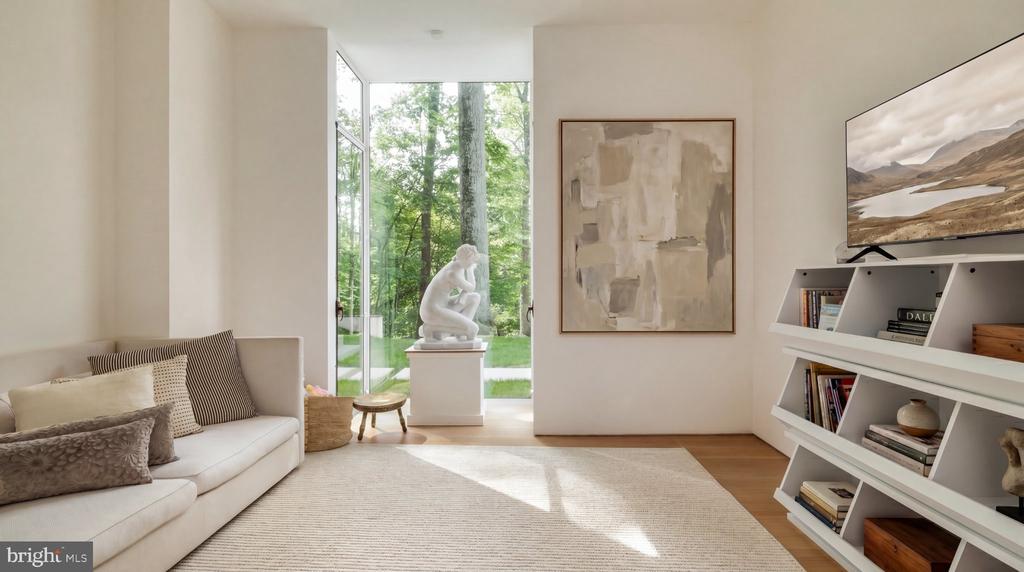 Bright living room with a cream sofa, tall garden-facing windows, and built-in shelving.
