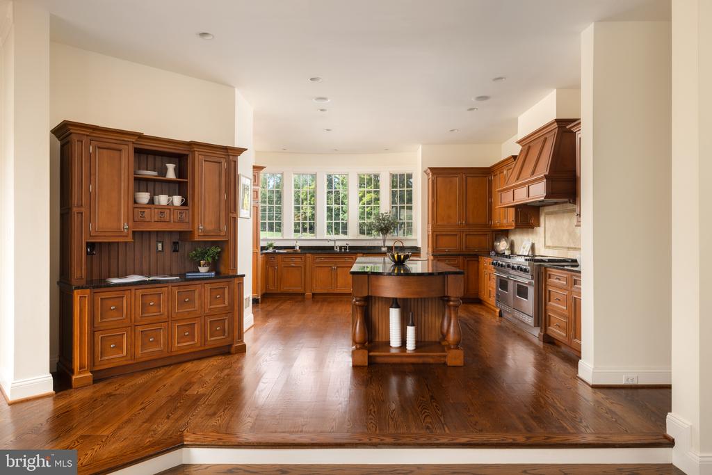 Spacious kitchen with rich wood cabinets, a central island, and large windows above the sink.