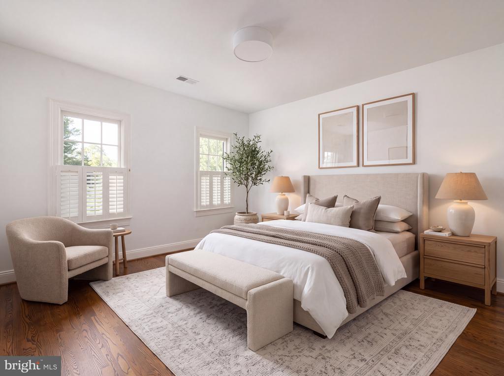 Staged bedroom with an upholstered bed, shuttered windows, and a bench at the foot.