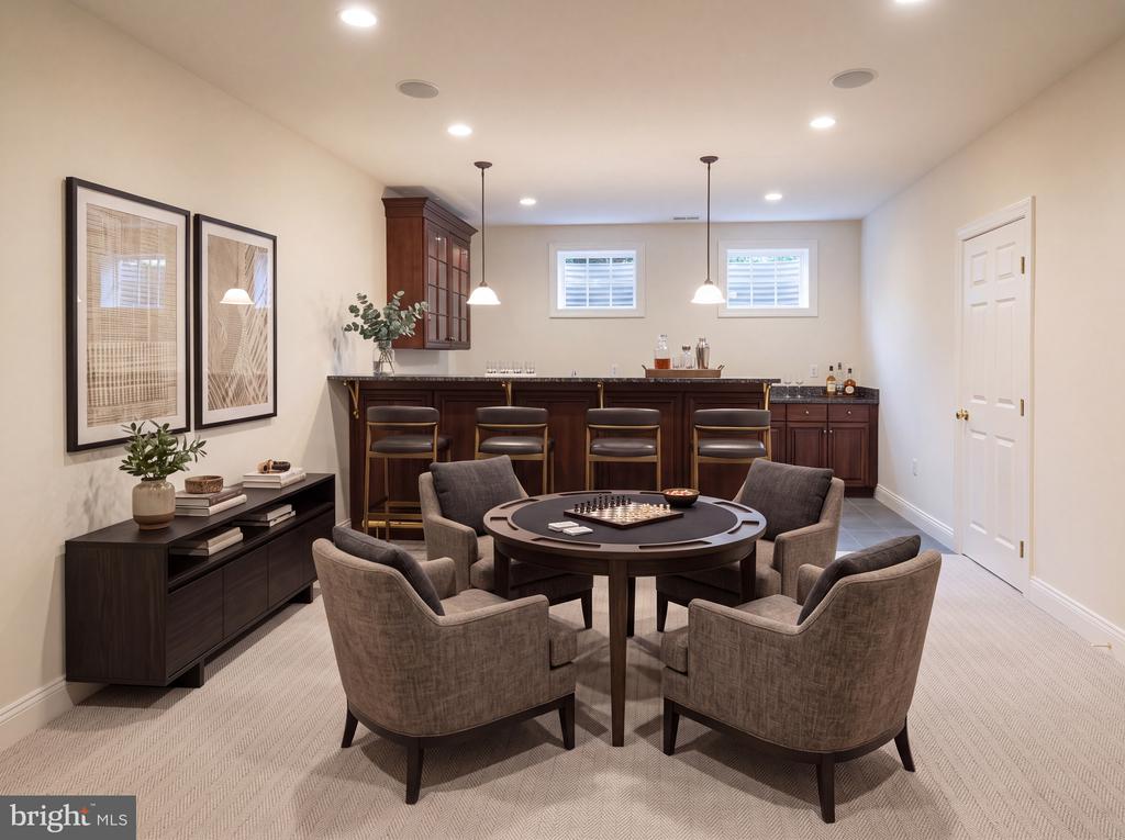 Game room with a dark wood bar and a round chess table surrounded by upholstered chairs.