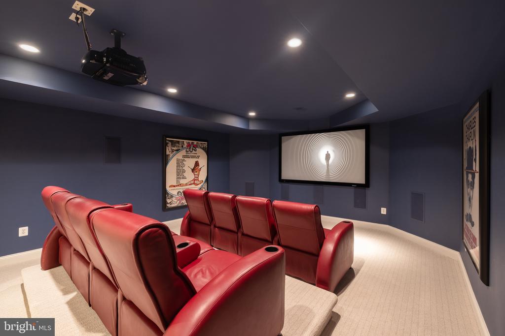 Home theater with red leather reclining seats facing a large projection screen.